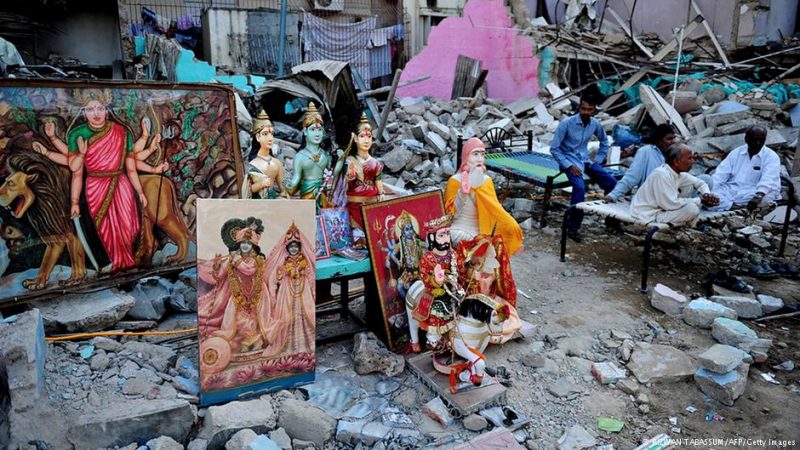 Pakistani Hindus sit next to the demolished temple in Karachi